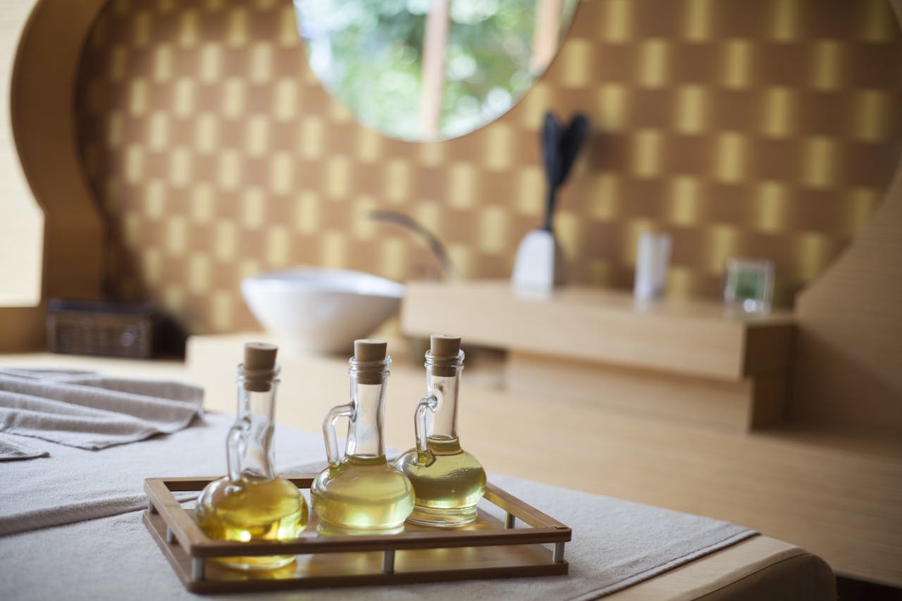 hero-img-01 Elegant indoor spa room with natural oil bottles on a wooden tray, exuding relaxation.